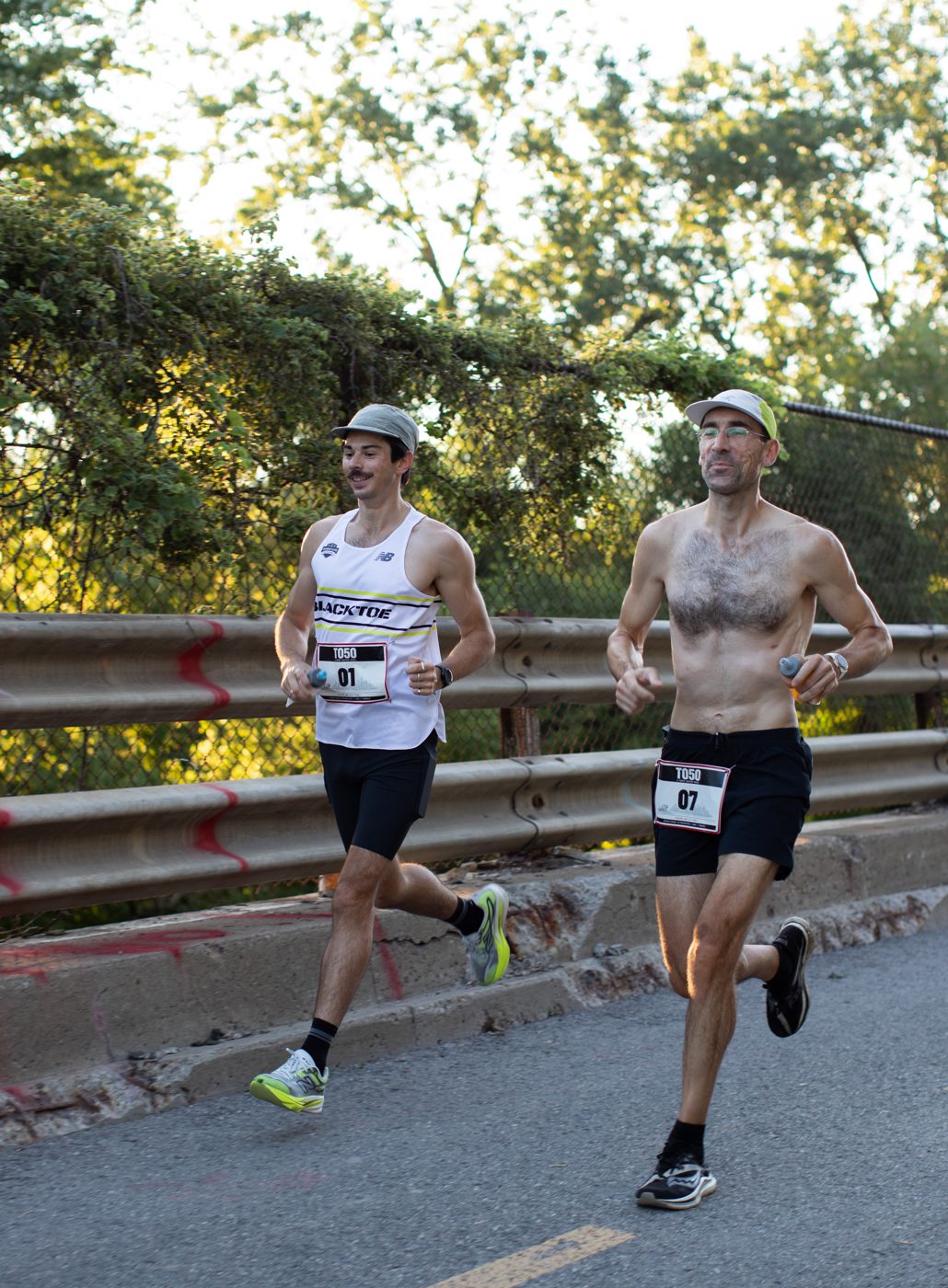 Runners 01 and 07 climbing a Toronto street in early morning light at the TO50 ultramarathon