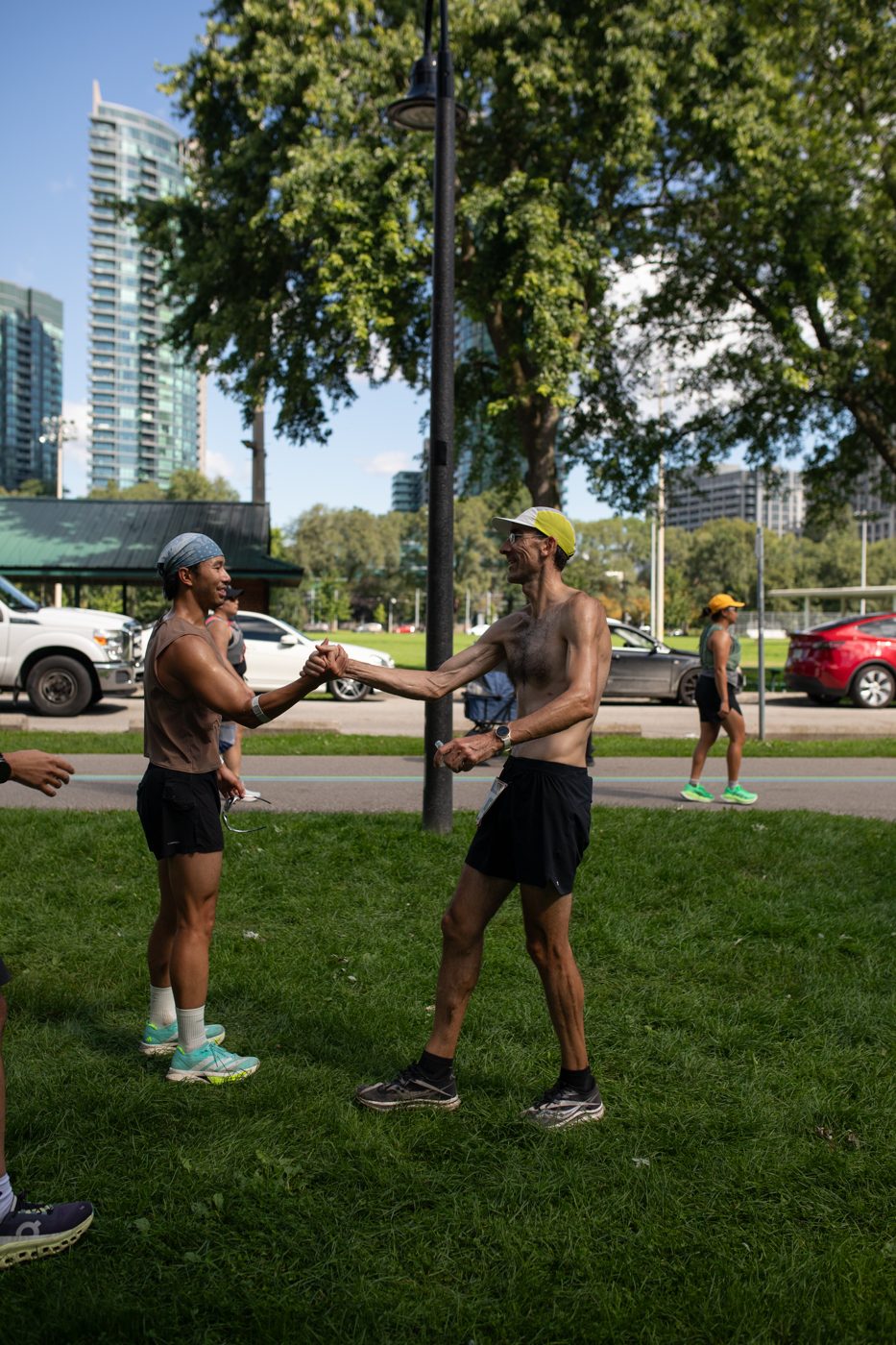 Runners shaking hands at the TO50 finish with the Toronto skyline behind them